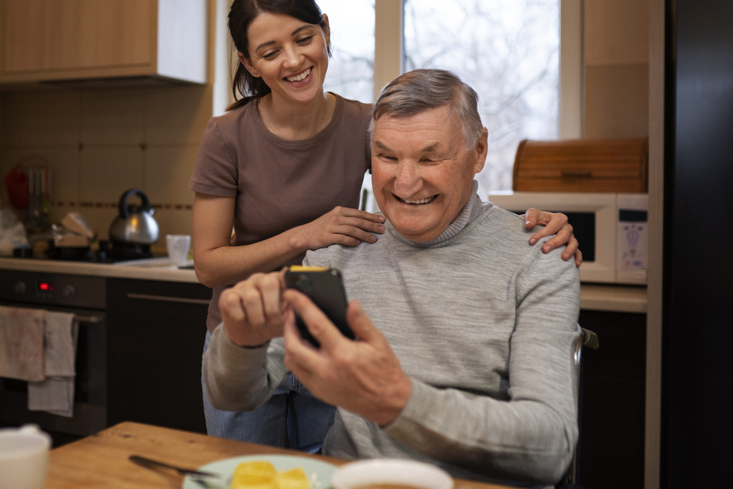 Senior ist am Smartphone gemeinsam mit Betreuung